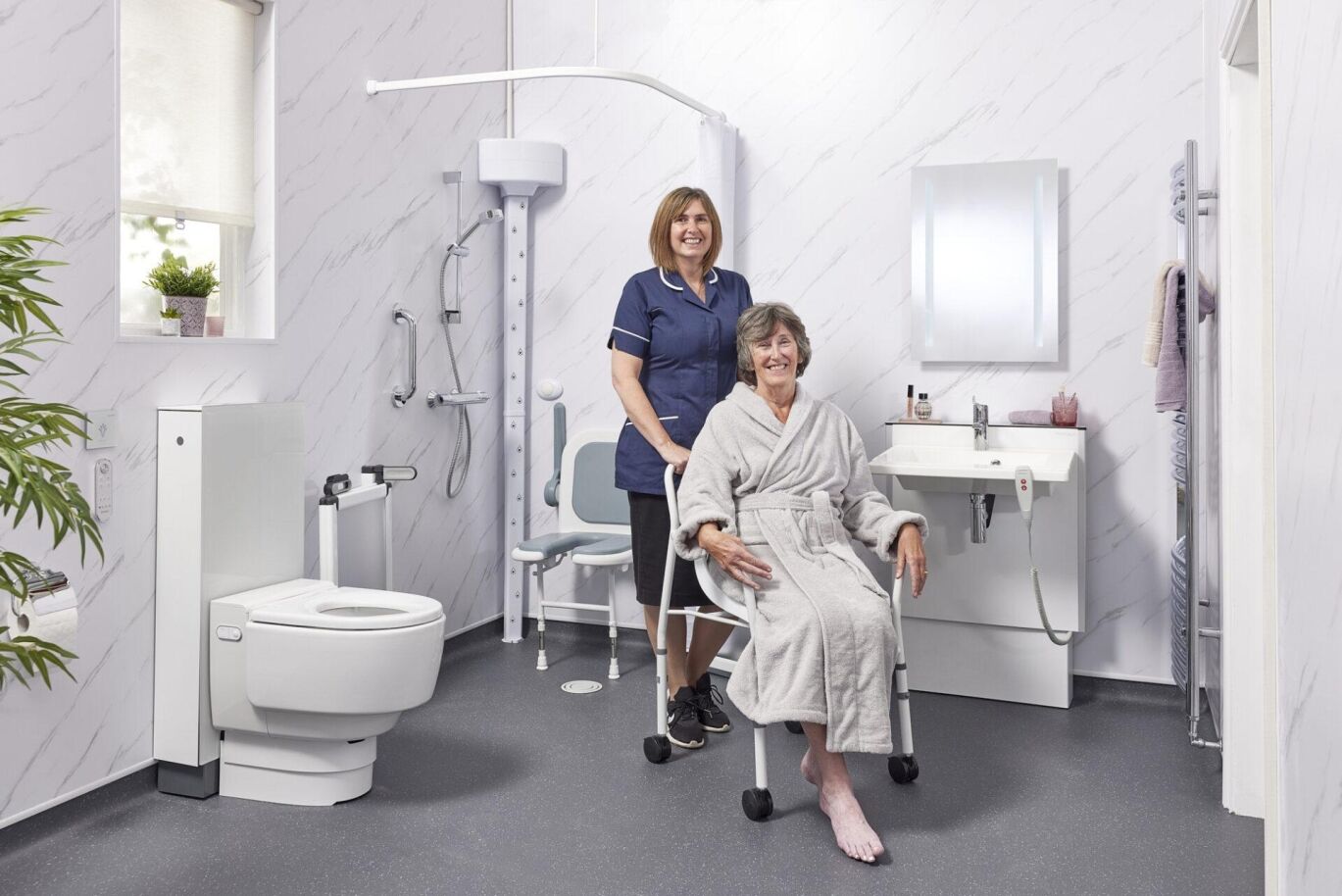 EA Mobility carer assisting an elderly woman in an accessible wet room with grab rails and a shower chair