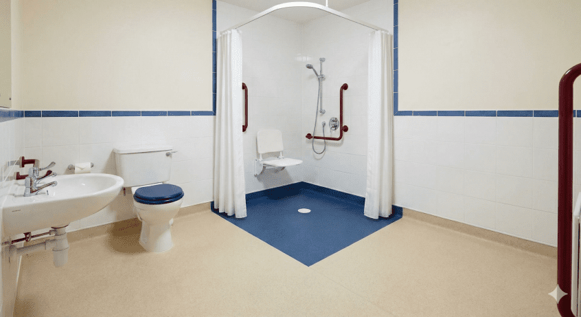 Dementia-friendly wet room floor featuring contrasting blue tiles in the shower area to clearly mark the wet zone.