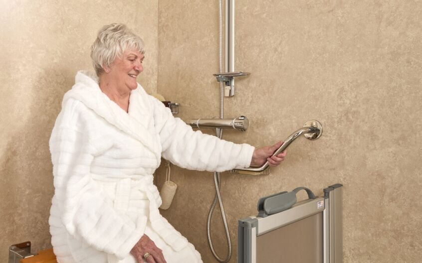 Elderly person holding onto a grab rail in a safety bathroom.