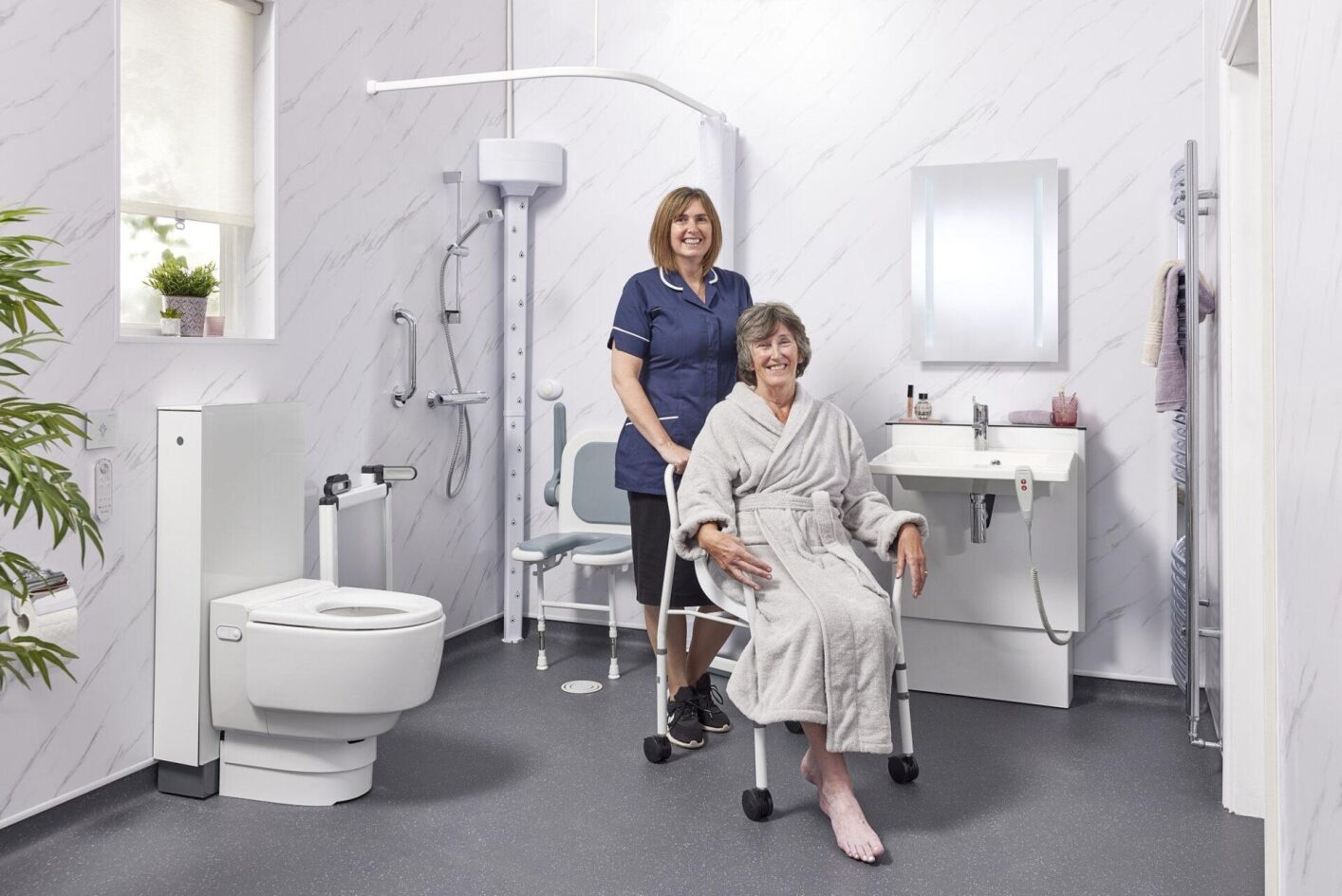 EA Mobility carer assisting an elderly woman in an accessible wet room with grab rails and a shower chair