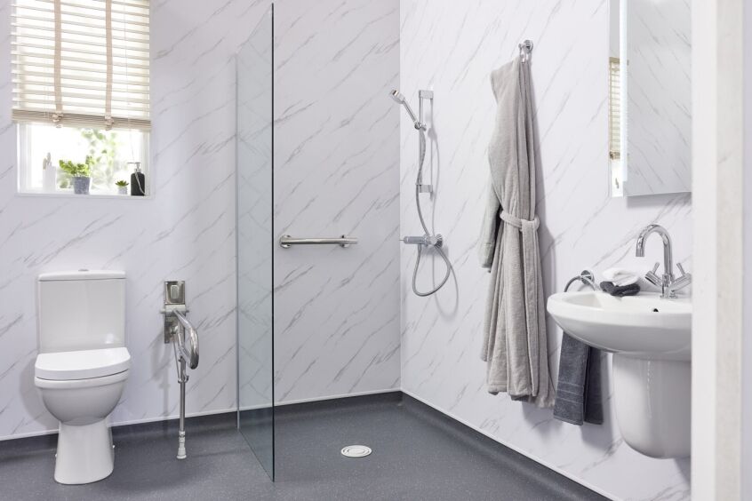 Small modern disabled wet room with marble-effect walls and a single fixed glass screen