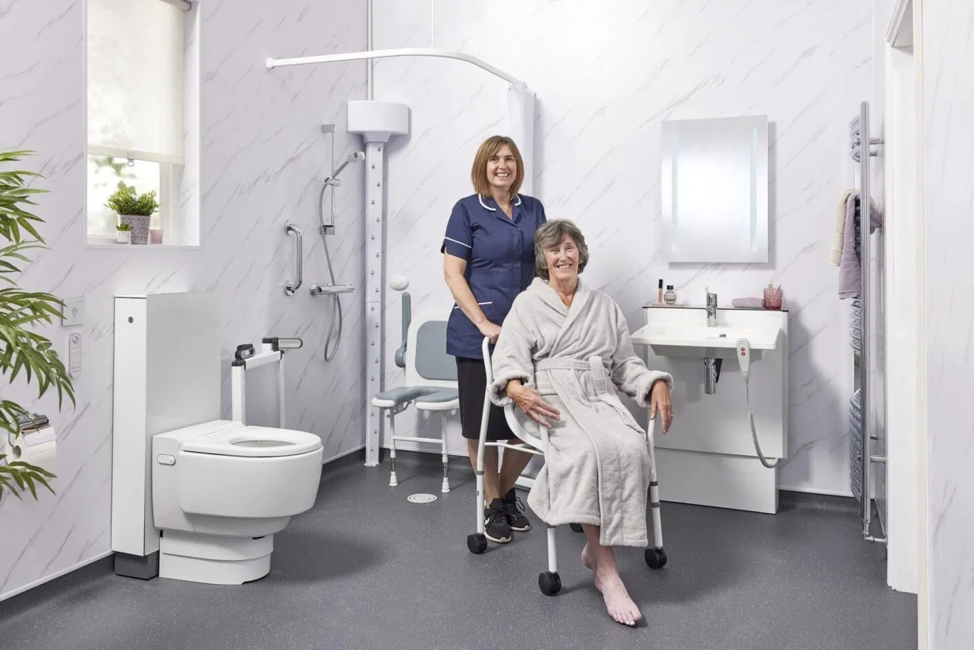 EA Mobility carer assisting an elderly woman in an accessible wet room with grab rails and a shower chair