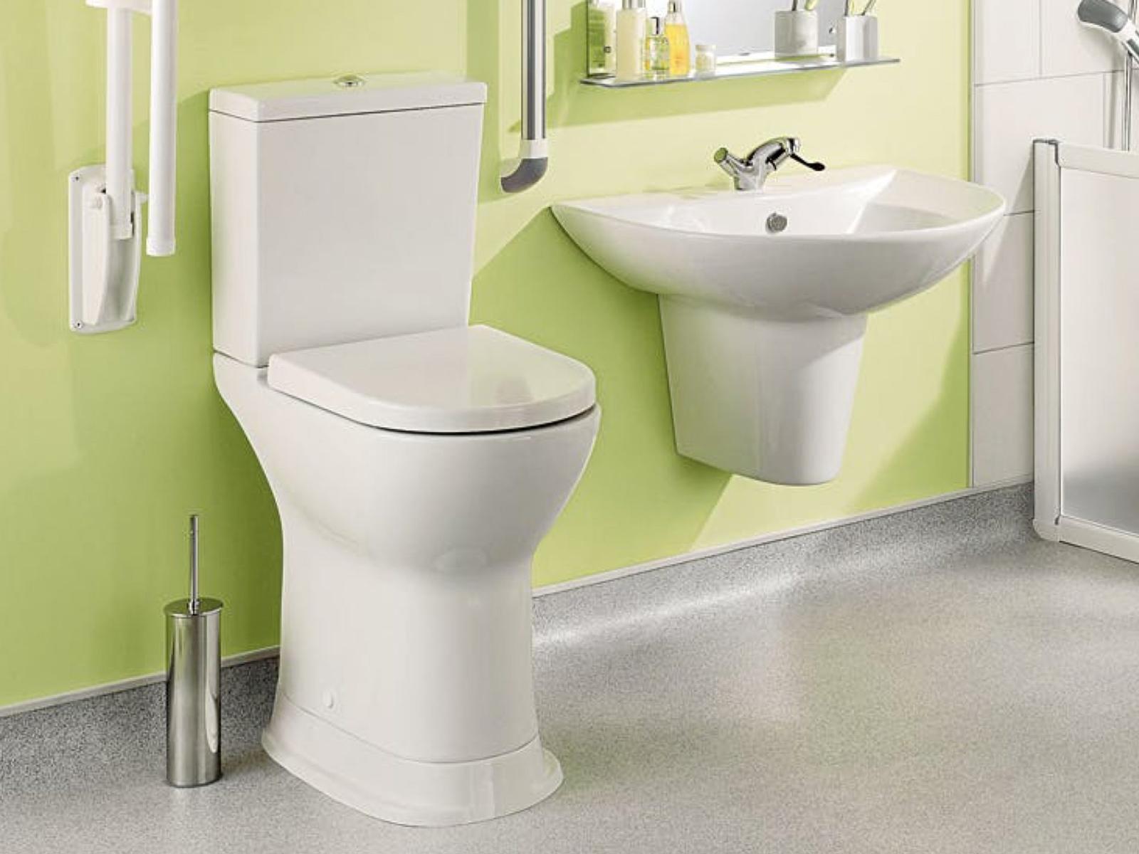 A toilet & sink in a green bathroom