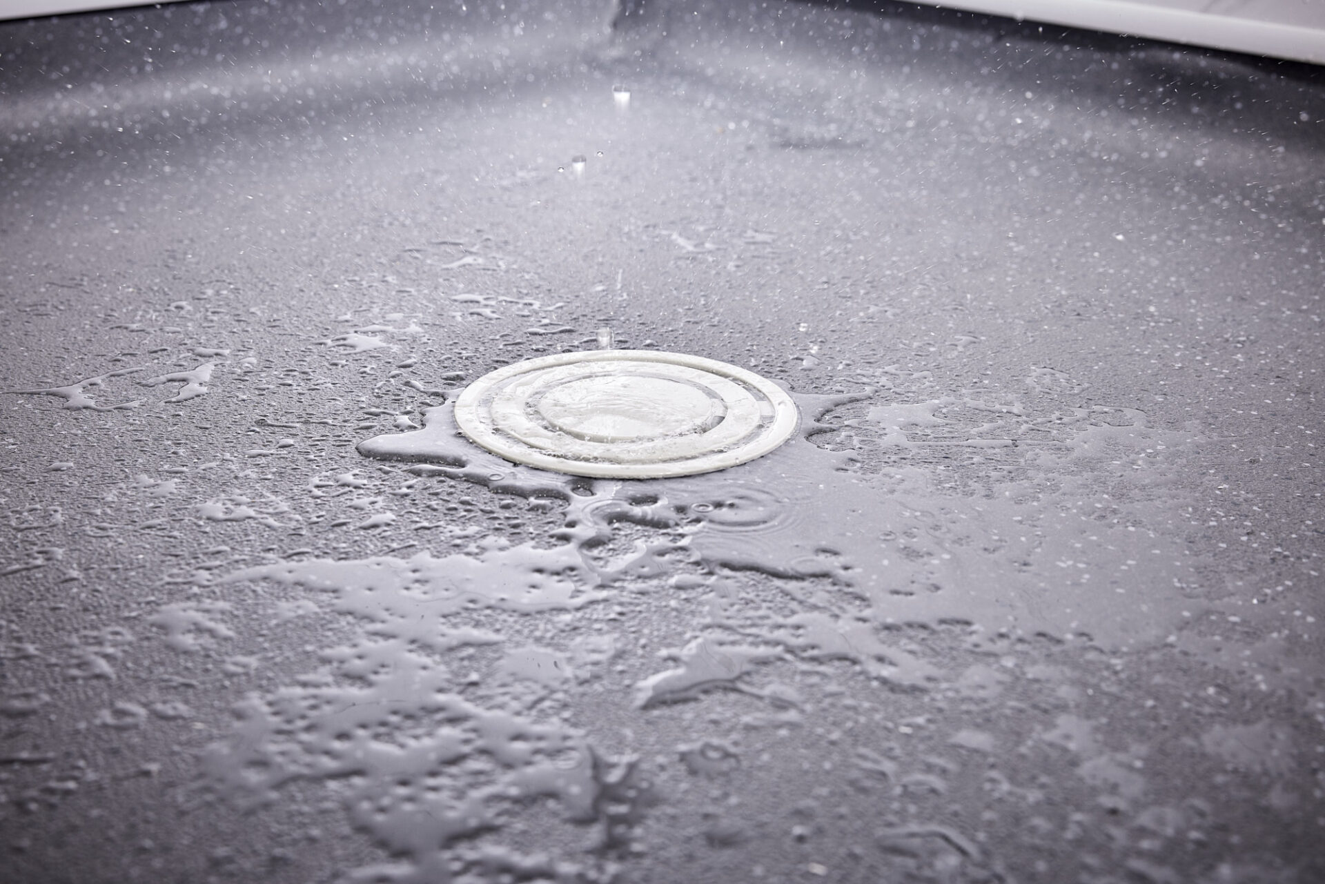 Close up of wet room drain system with water splashing