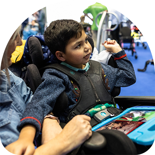 Older woman in bathrobe standing beside level-access shower with fold-down seat, grab rails, and anti-slip blue flooring in accessible bathroom